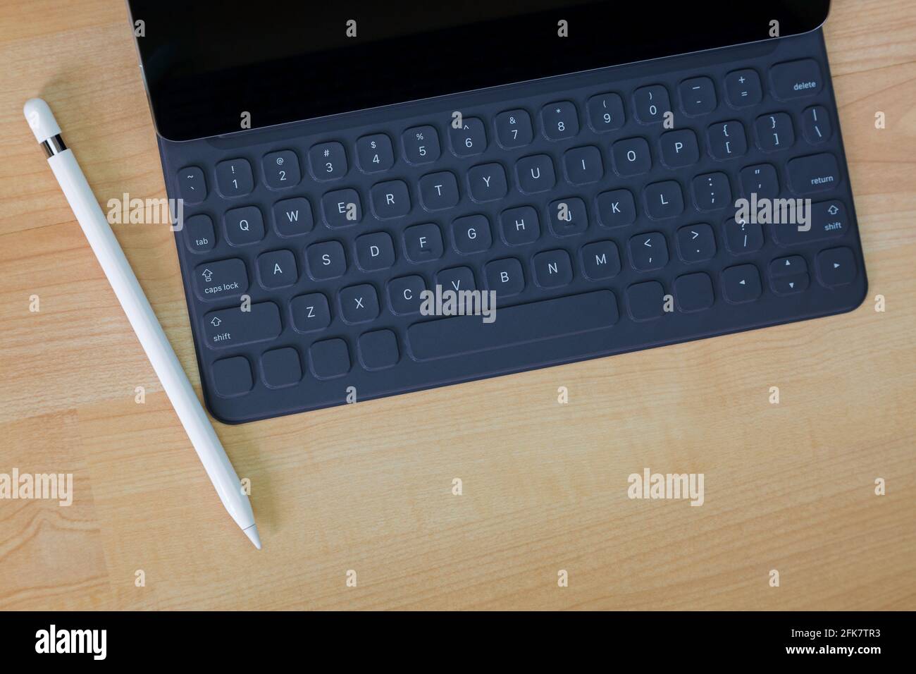 Black pro tablet computer connecting on portable keyboard next to white pencil pen on wooden background with copyspace Stock Photo