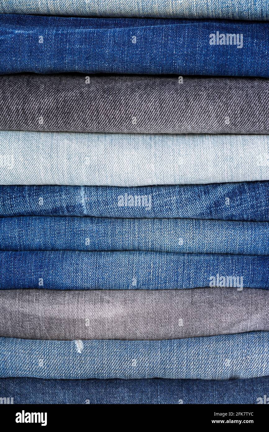 Closeup stack of folded clothes, blue jeans pants texture, dark blue denim trousers Stock Photo