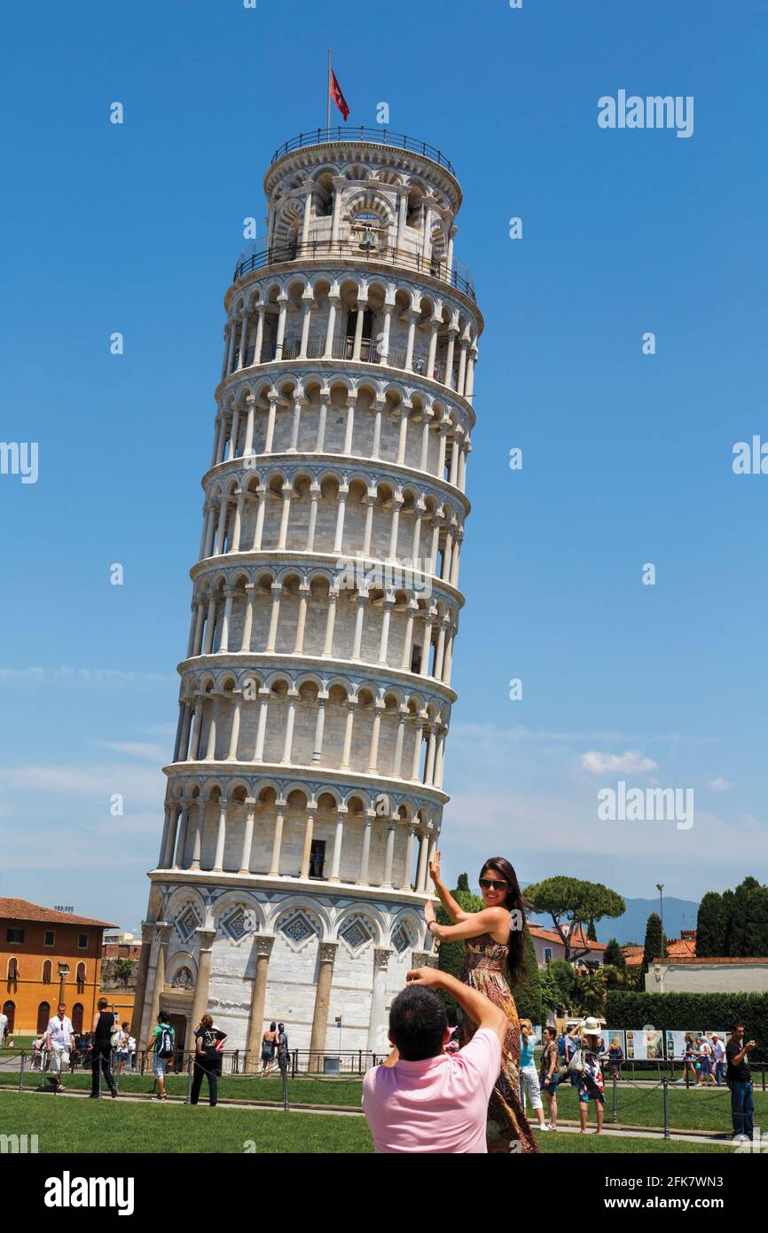 Pisa, Pisa Province, Tuscany, Italy.  Tourists playing at holding up the Leaning Tower of Pisa.  The  tower is the belltower (campanile) of the Duomo, Stock Photo