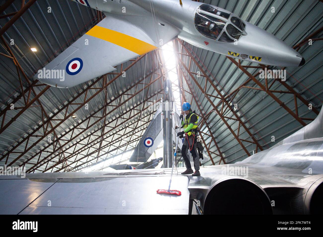 Specialist operators at the Royal Air Force Museum Cosford, near Telford, Shropshire, clean the Avro Vulcan aircraft situated below the Hawker Hunter aircraft, displayed within the museum's National Cold War Exhibition, during annual high-level aircraft cleaning and maintenance. Picture date: Thursday April 29, 2021. Stock Photo