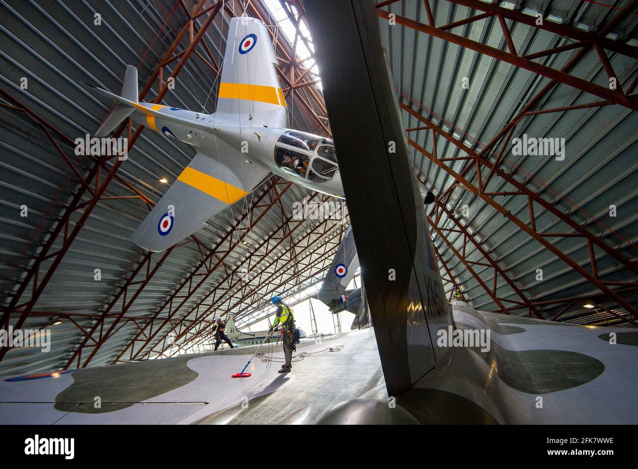Specialist operators at the Royal Air Force Museum Cosford, near Telford, Shropshire, clean the Avro Vulcan aircraft situated below the Hawker Hunter aircraft, displayed within the museum's National Cold War Exhibition, during annual high-level aircraft cleaning and maintenance. Picture date: Thursday April 29, 2021. Stock Photo