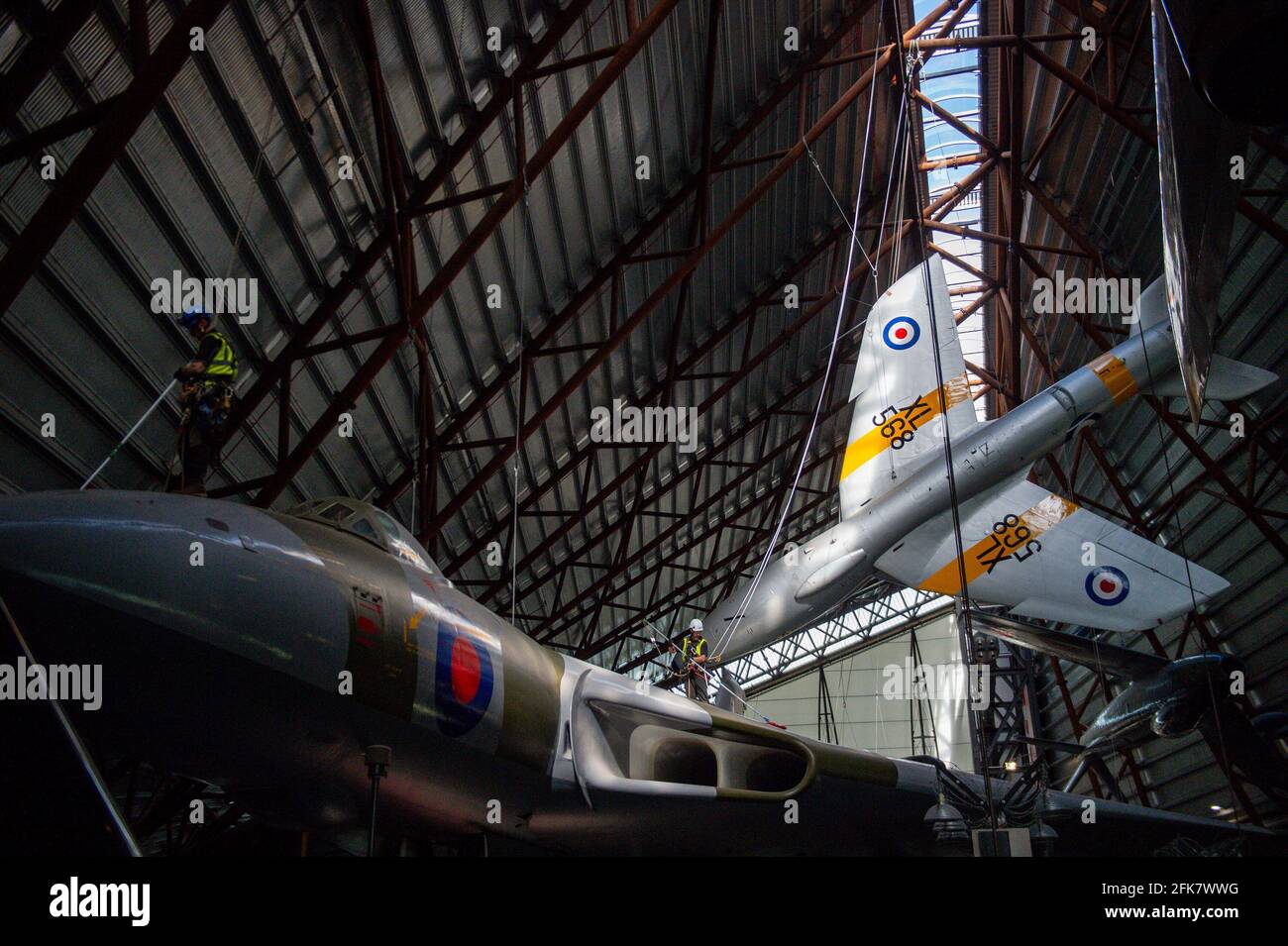 Specialist operators at the Royal Air Force Museum Cosford, near Telford, Shropshire, clean the Avro Vulcan aircraft situated below the Hawker Hunter aircraft, displayed within the museum's National Cold War Exhibition, during annual high-level aircraft cleaning and maintenance. Picture date: Thursday April 29, 2021. Stock Photo