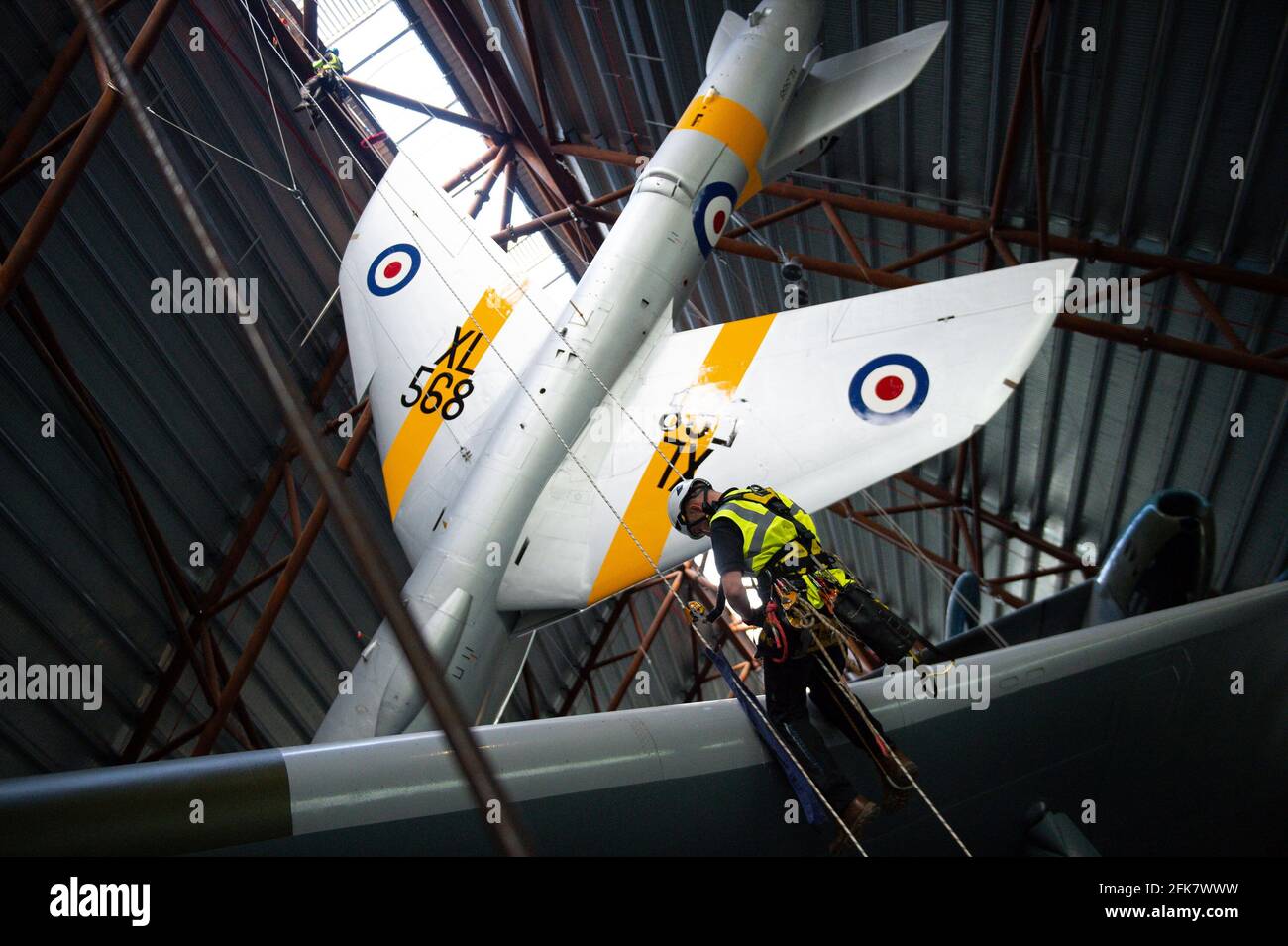 Specialist operators at the Royal Air Force Museum Cosford, near Telford, Shropshire, clean the Avro Vulcan aircraft situated below the Hawker Hunter aircraft, displayed within the museum's National Cold War Exhibition, during annual high-level aircraft cleaning and maintenance. Picture date: Thursday April 29, 2021. Stock Photo