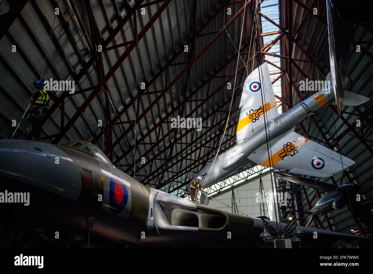 Specialist operators at the Royal Air Force Museum Cosford, near Telford, Shropshire, clean the Avro Vulcan aircraft situated below the Hawker Hunter aircraft, displayed within the museum's National Cold War Exhibition, during annual high-level aircraft cleaning and maintenance. Picture date: Thursday April 29, 2021. Stock Photo