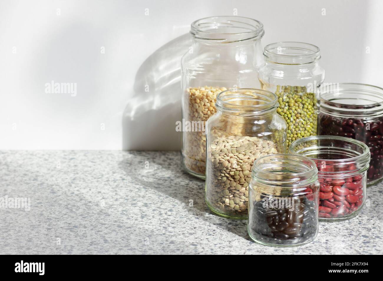 Variety of dry legumes: kidney bean, peas, green gram in glass jars uncooked on white kitchen background, zero waste, eco friendly, balanced diet food Stock Photo
