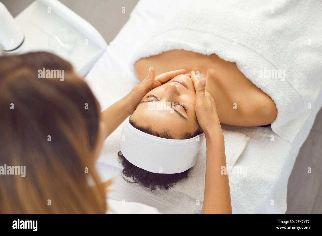Young beautiful woman has relaxed and is enjoying a facial massage from a spa specialist. Stock Photo