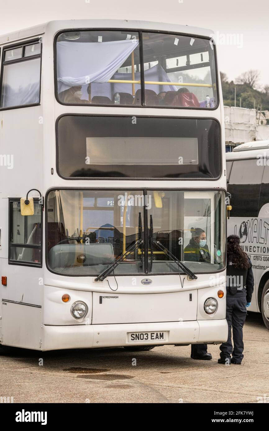 Migrants who have just crossed the English Channel from France are put on buses and taken to be processed at Dover Marina, Kent, UK. Stock Photo