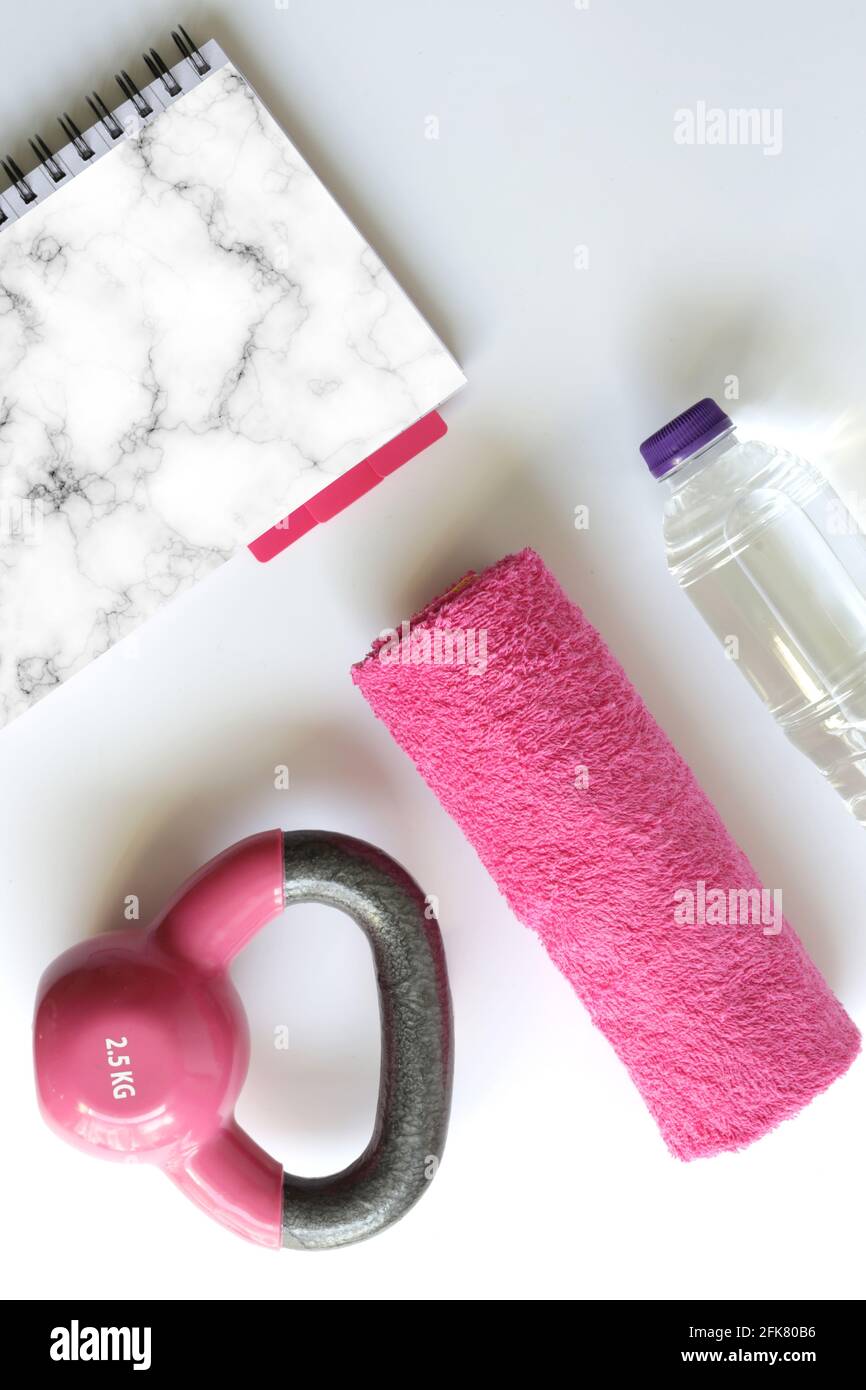 sport feminine accessories, flat lay, Pink dumbbell pink notepad for mock up, copy space. Gym accessory and equipment in pink feminine color. Fitness Stock Photo