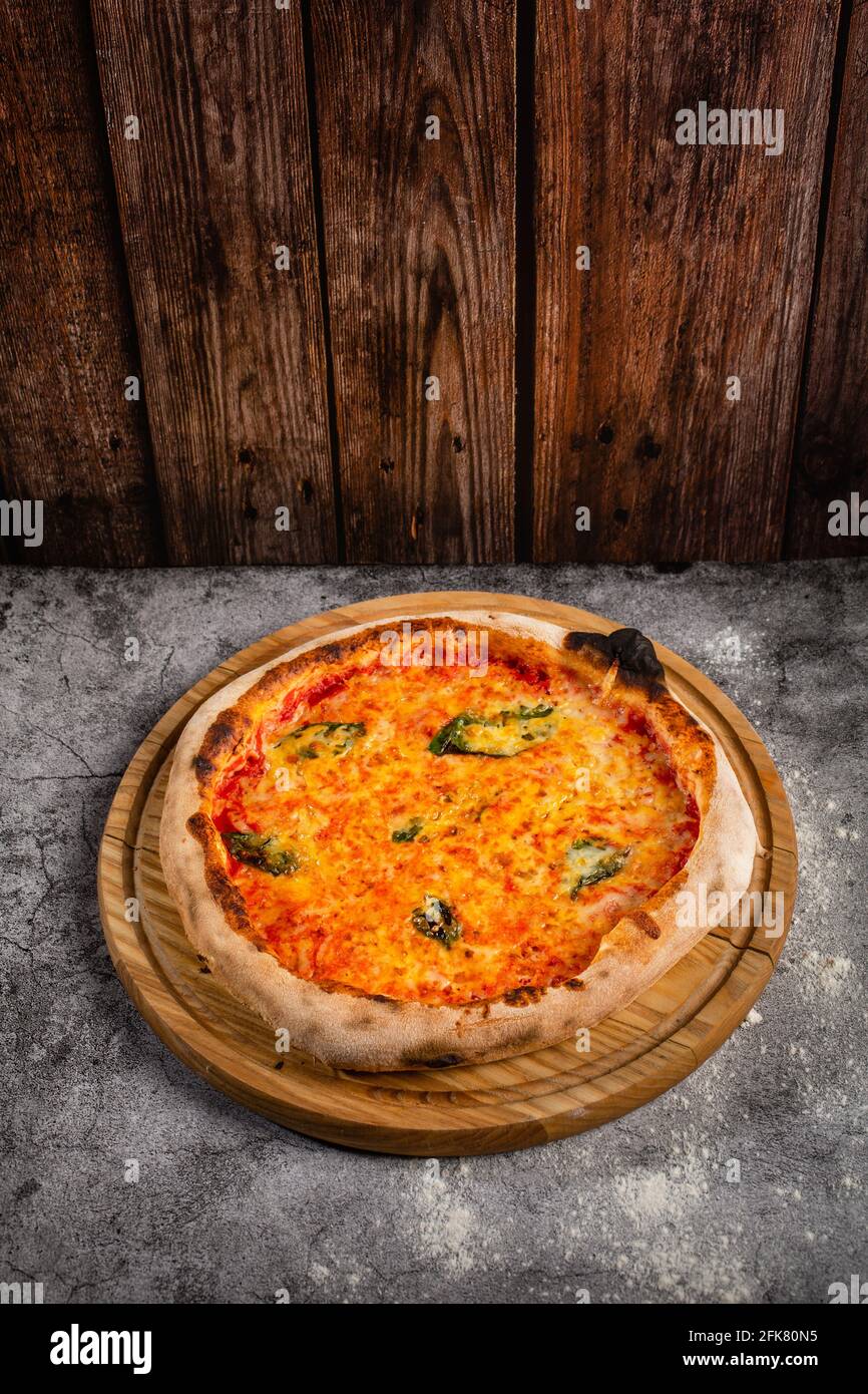 Classic homemade Italian cheese pizza fresh out of the oven. Pizza with cheese and basil leaves. The concept of nutritious food. Stock Photo