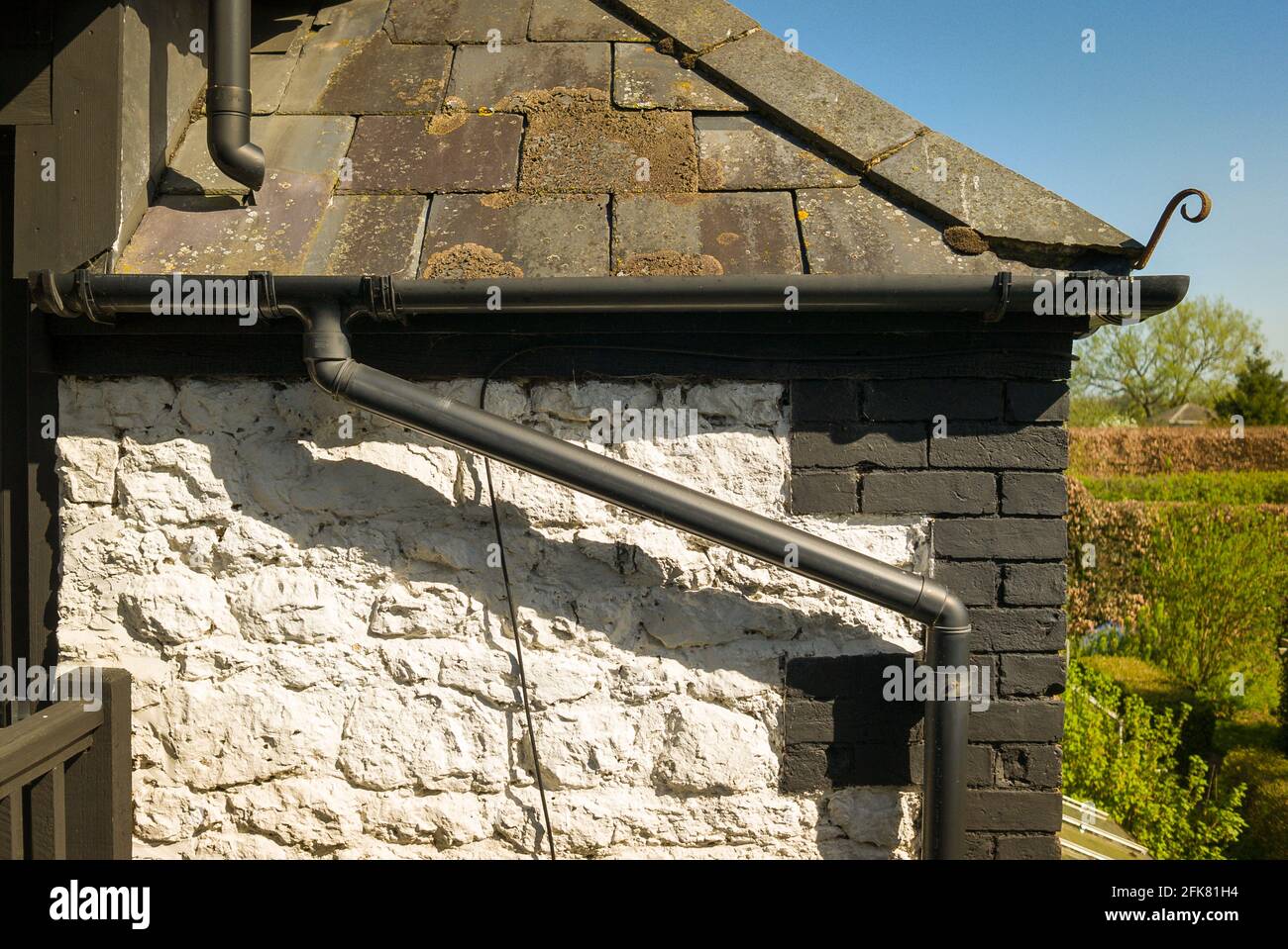 Rainwater collection from the roof of an old Victorian brick and stone-built  barn, aided by guttering and down pipes Stock Photo