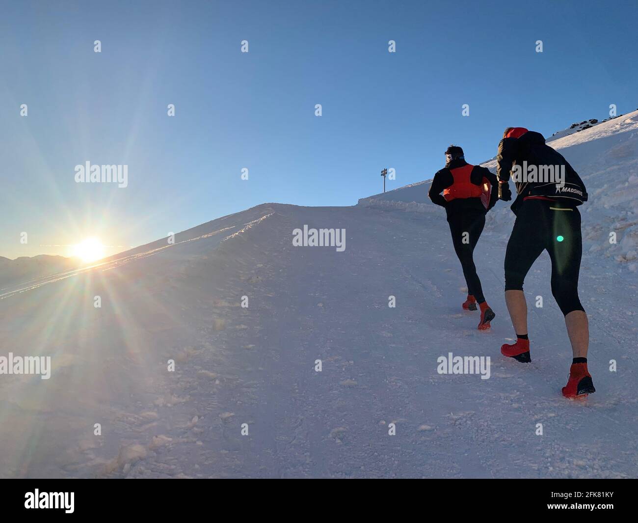 A man and a woman hiking up a snowy slope of french alps during winters. Stock Photo