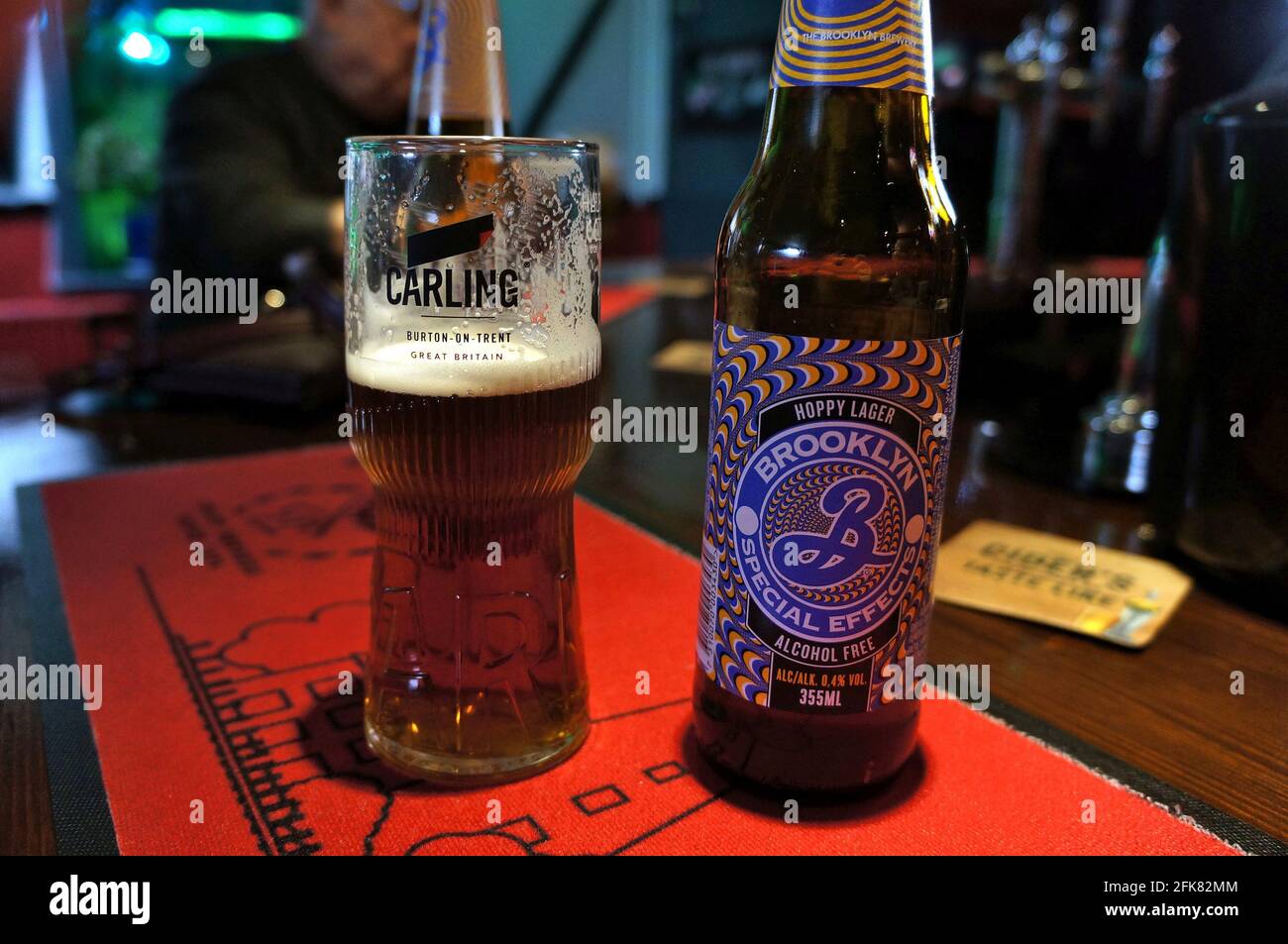 Brooklyn alcohol-free beer bottle and pint glass at the bar on a soft-focused background Stock Photo