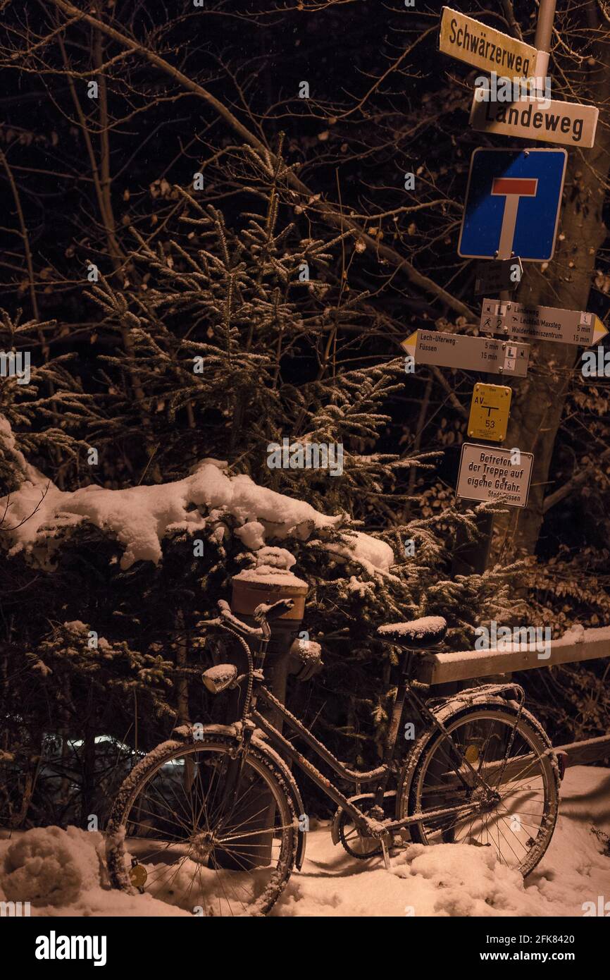 Street signs and a bicycle on one snowy night in Füssen, south of Germany. Stock Photo
