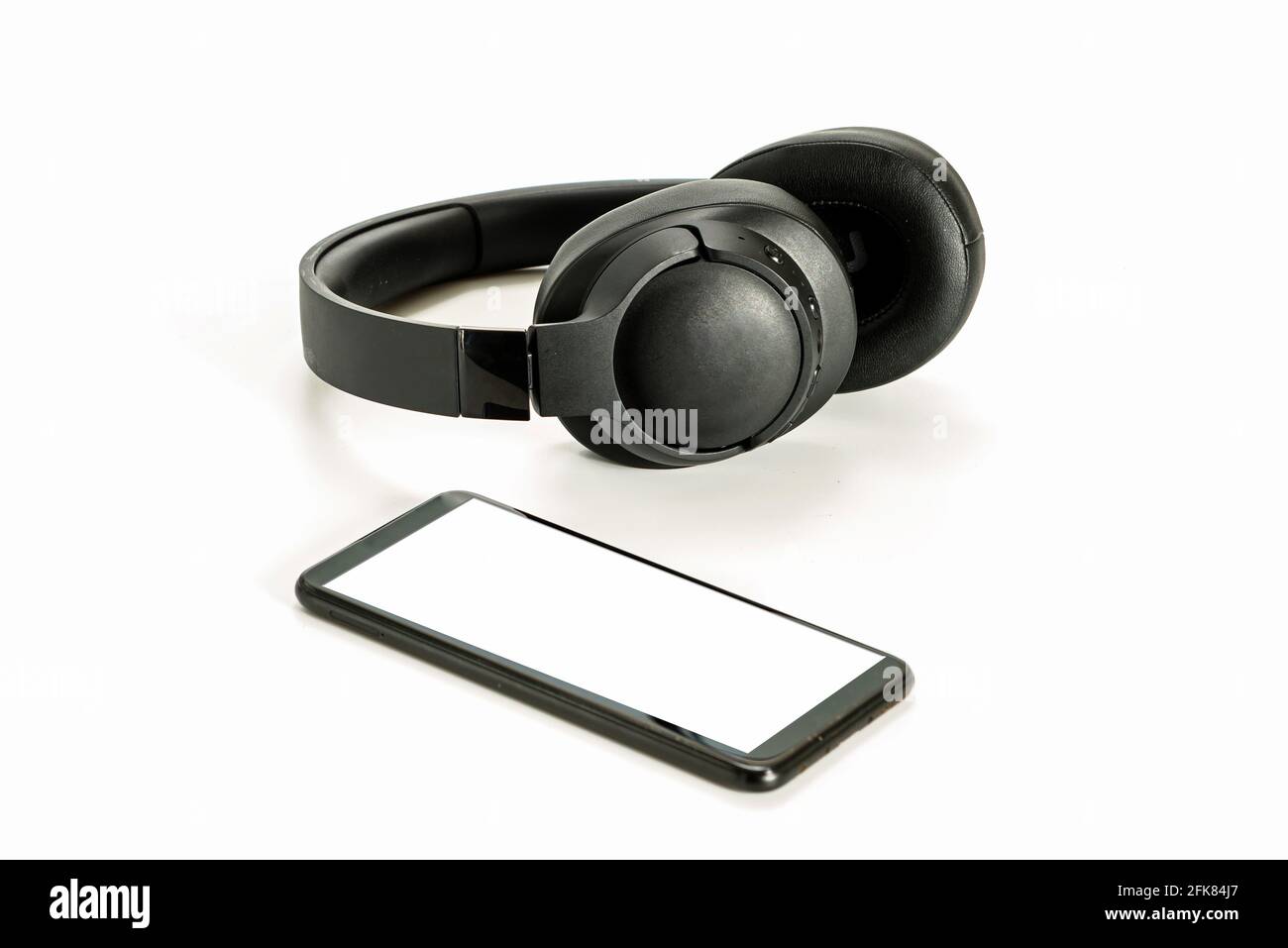 black wireless headphones and smartphone on white background, blank screen mockup, copy space Stock Photo