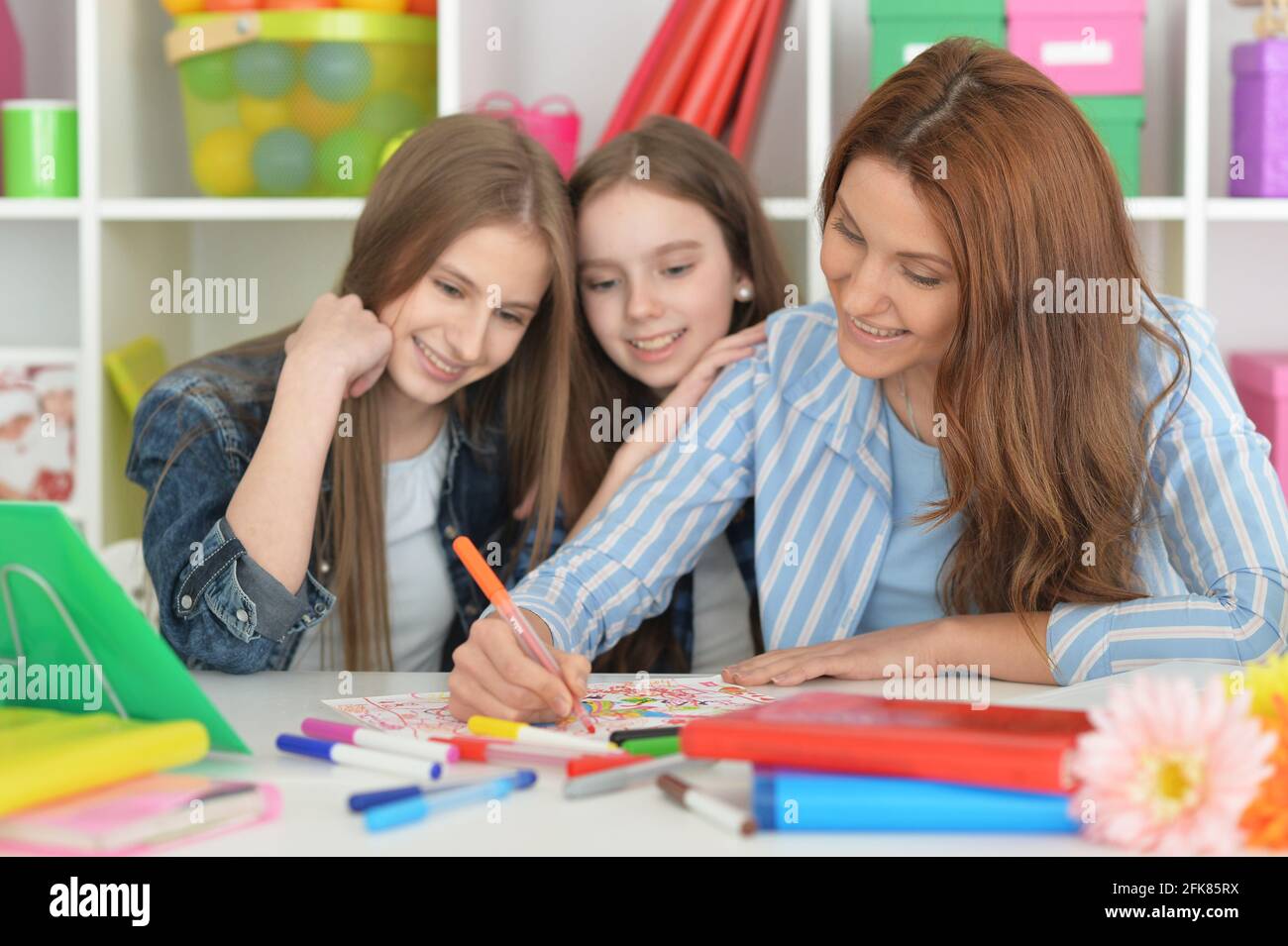 Teacher with two girls drawing together at art class Stock Photo - Alamy