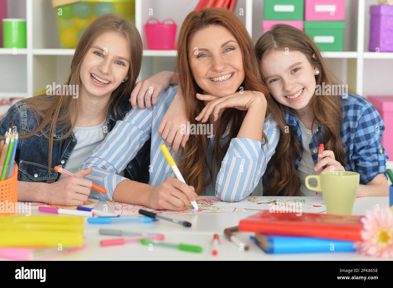 Teacher with two girls painting together at art class Stock Photo - Alamy