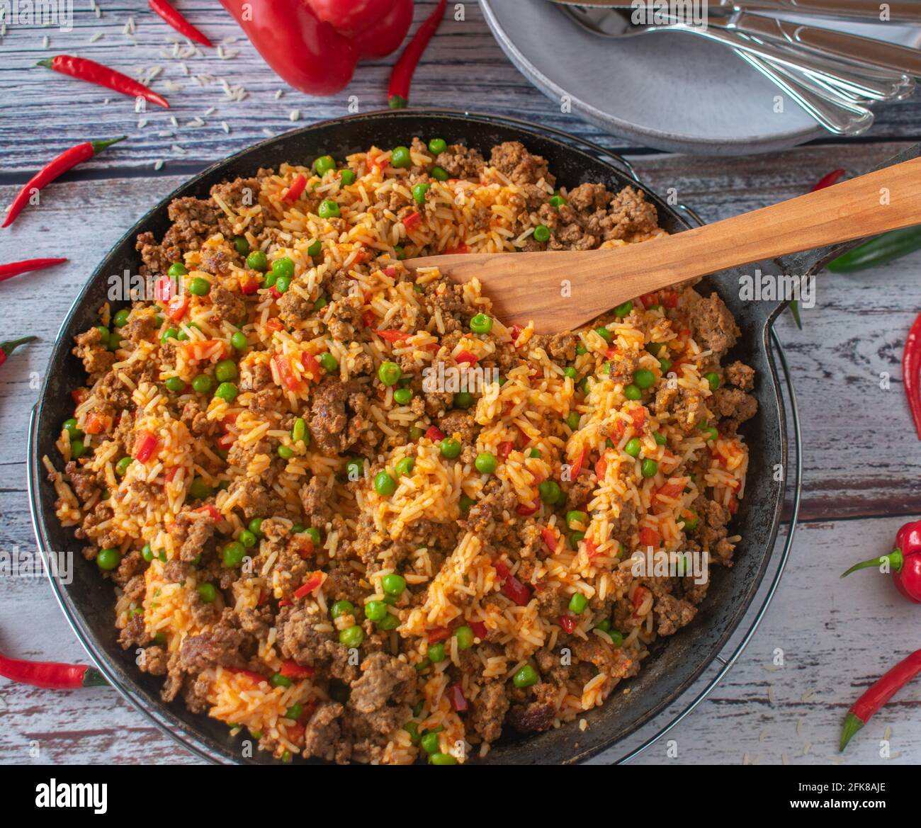 Mediterranean pan dish with serbian djuvec rice and spicy minced meat served in a rustic cast iron skillet on weathered wooden background. Stock Photo
