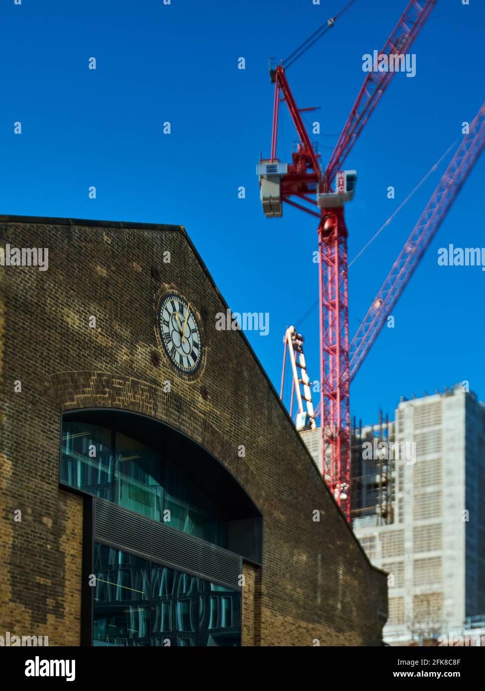 A tower crane helps to assemble the central core of a new building behind the facade of an old warehouse, repurposed during an urban renewal project. Stock Photo