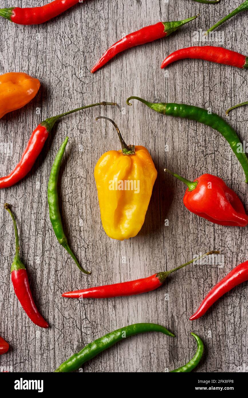 high angle view of different chili peppers on a gray rustic wooden table Stock Photo