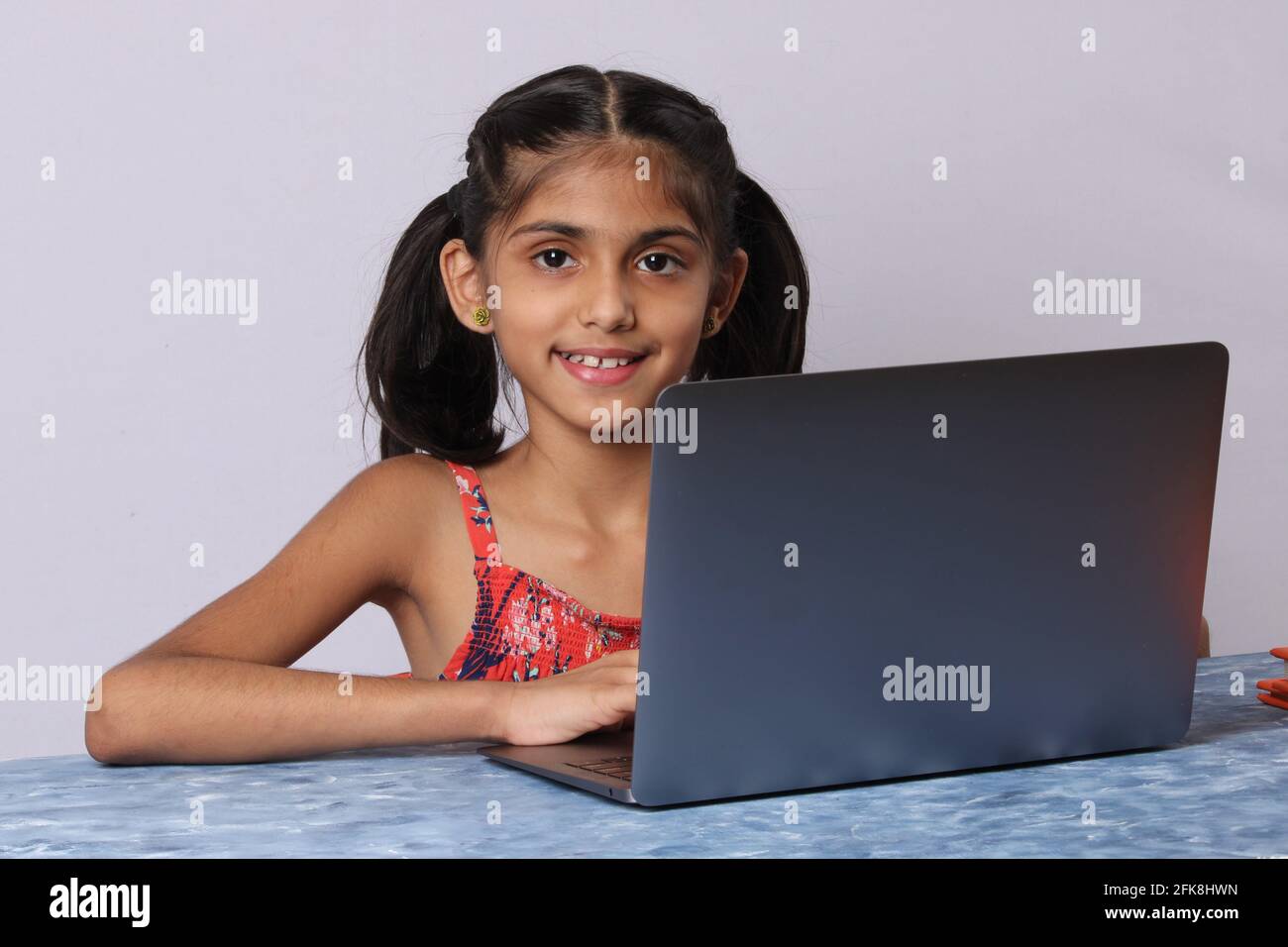 Little girl studying online using her laptop or computer at home Stock ...