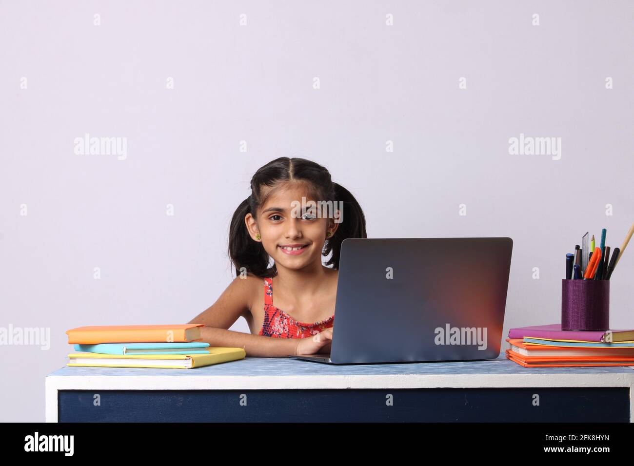 Little girl studying online using her laptop or computer at home Stock ...