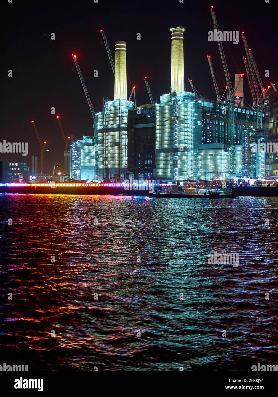 The iconic Battersea power station, illuminated with artificial lights, clad in hoardings and surrounded by cranes as it undergoes redevelopment. Stock Photo