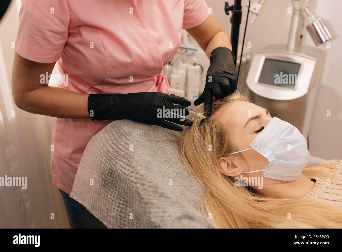 Injection against hair loss in head of blonde woman in clinic. Stock Photo