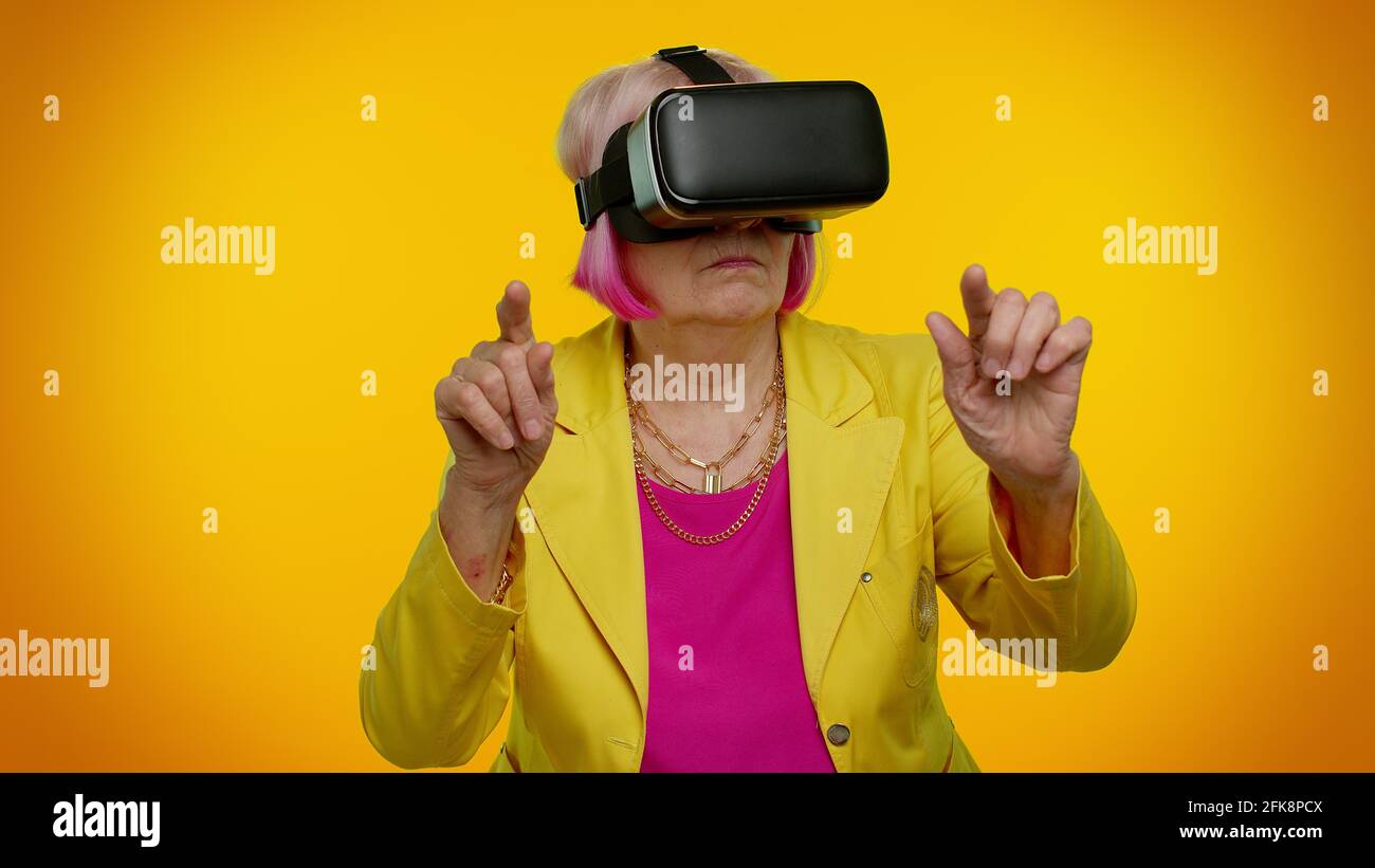 Senior woman using virtual reality VR app headset helmet to play ...