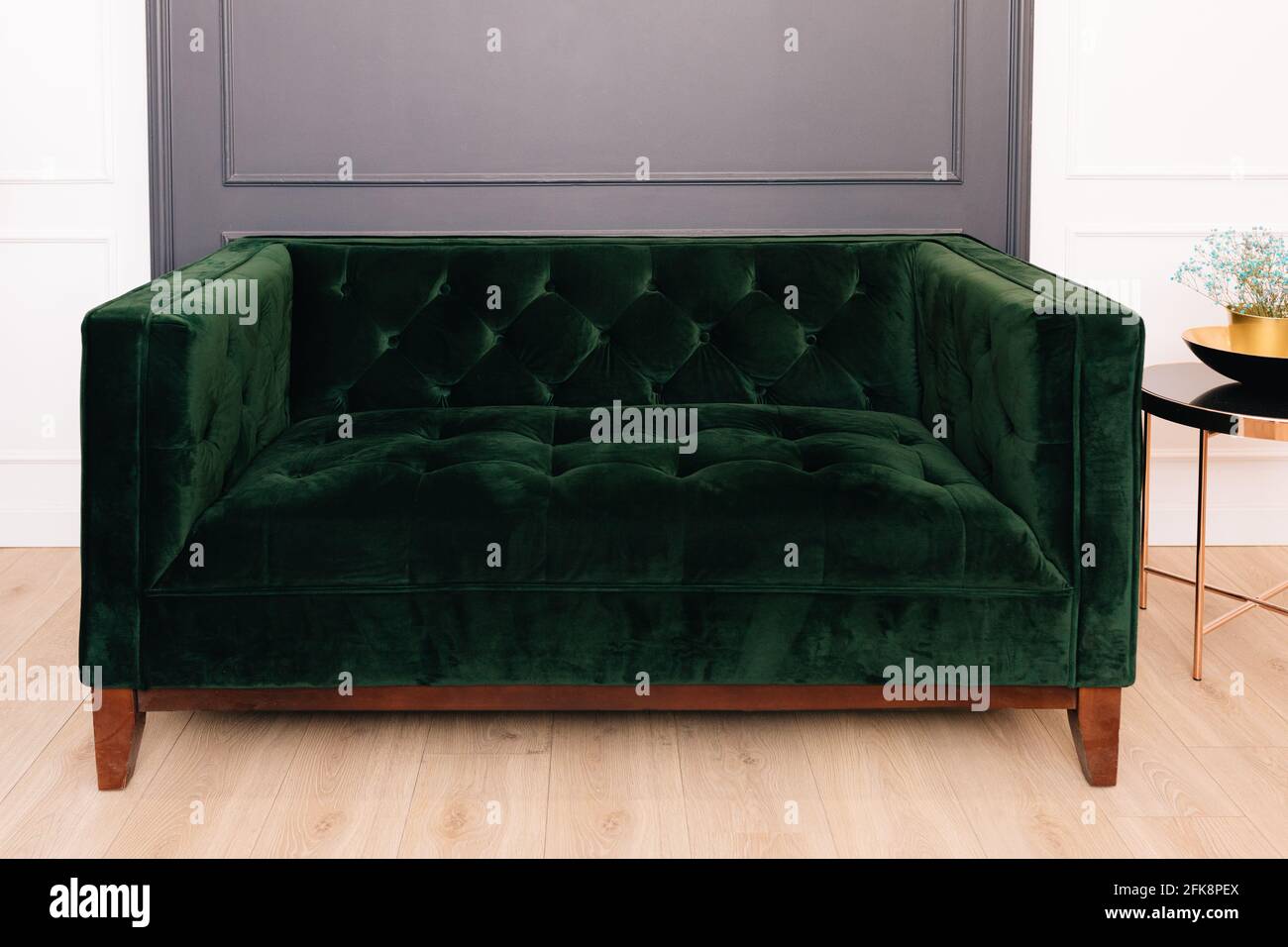 Dark green malachite velor sofa in the interior. Capitone textile, suede, velour, with buttons Stock Photo