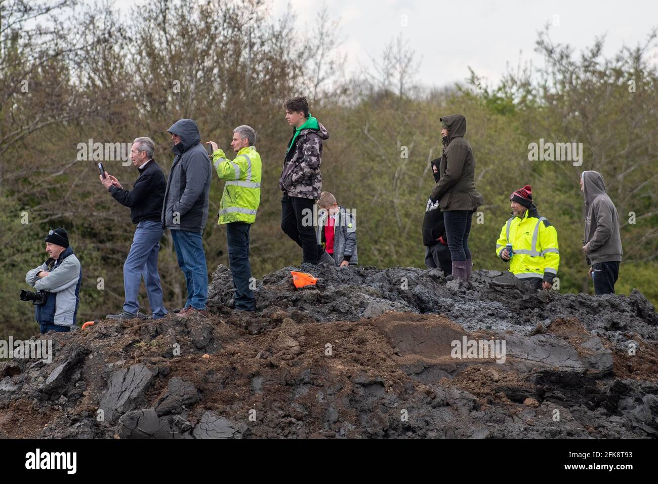 People look on as a 26-foot-long Buffalo tank is extracted from the earth in Crowland, Lincolnshire, where it has been buried for 74 years since it was brought into the village to help during heavy floods in March 1947. Sixteen of the amphibious Buffalo tanks were used to help seal the breach when a combination of heavy snow, high tides, rain and wind caused the River Welland to break its banks. Picture date: Thursday April 29, 2021. Stock Photo