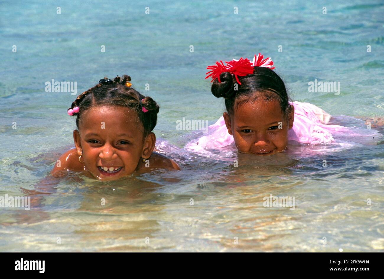 Dominikanische Republik, badende einheimische Kinder am Strand bei Puerto Plata. Im Haar tragen sie traditonellen einheimischen Kinder-Schmuck. Stock Photo