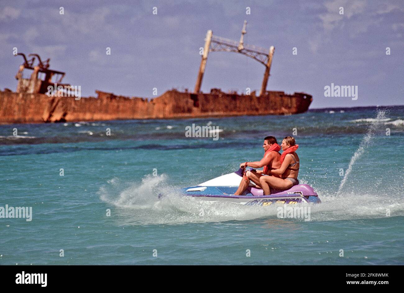 Dominikanische Republik, Wassermoped mit Urlaubern und Schiffswrack, vor der Kueste von Punta Cana. Stock Photo