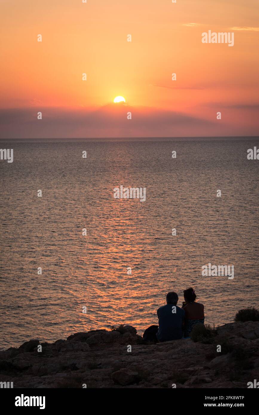 Ein Paar im Sonnenuntergang an einem Aussichtspunkt von Ibiza - a couple at sunset at a viewpoint at Ibiza Stock Photo