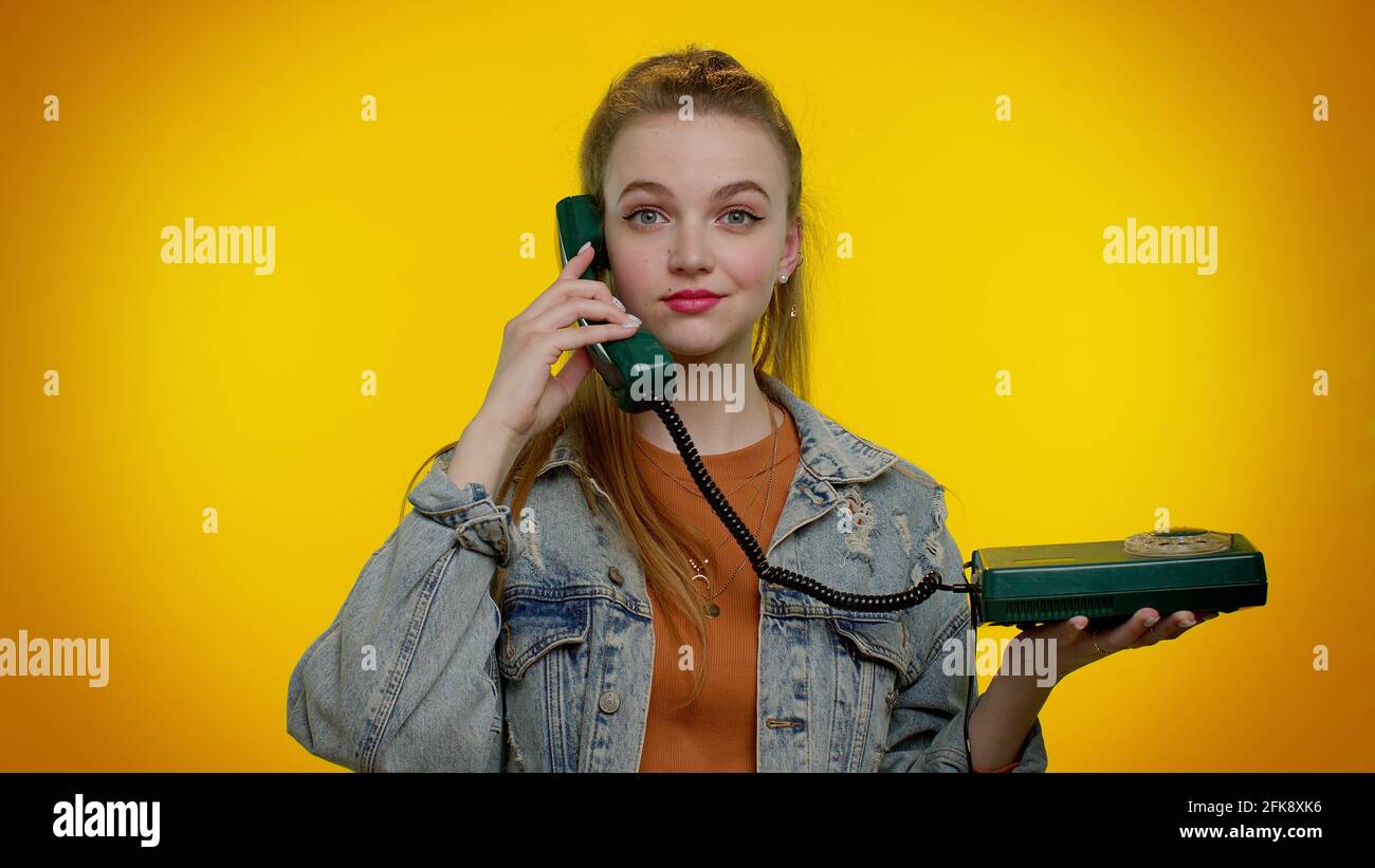 Cheerful teen girl secretary talking on wired vintage telephone of 80s, says hey you call me back Stock Photo