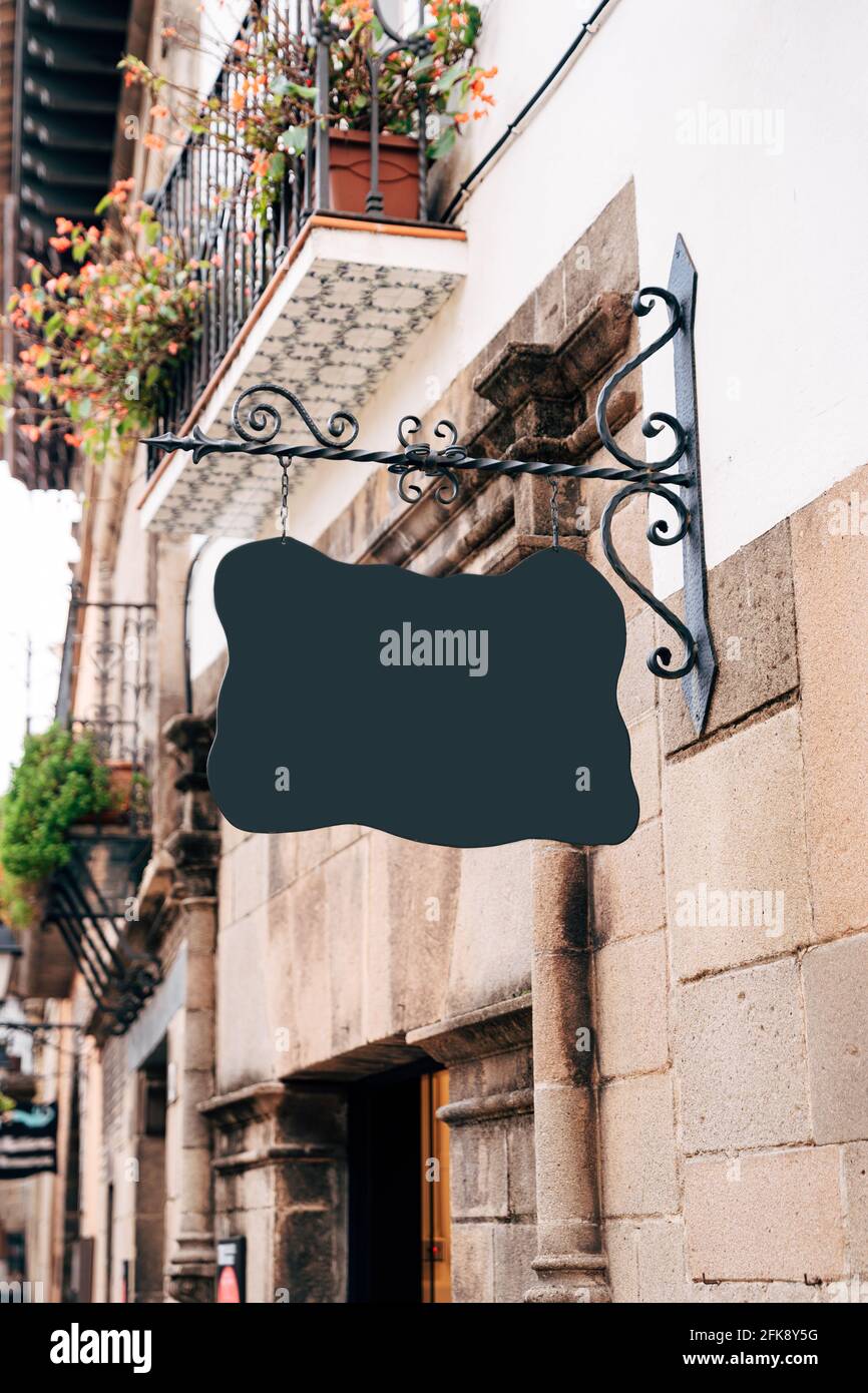Empty signboard of a bizarre shape hangs on a beautiful forged pin on ...