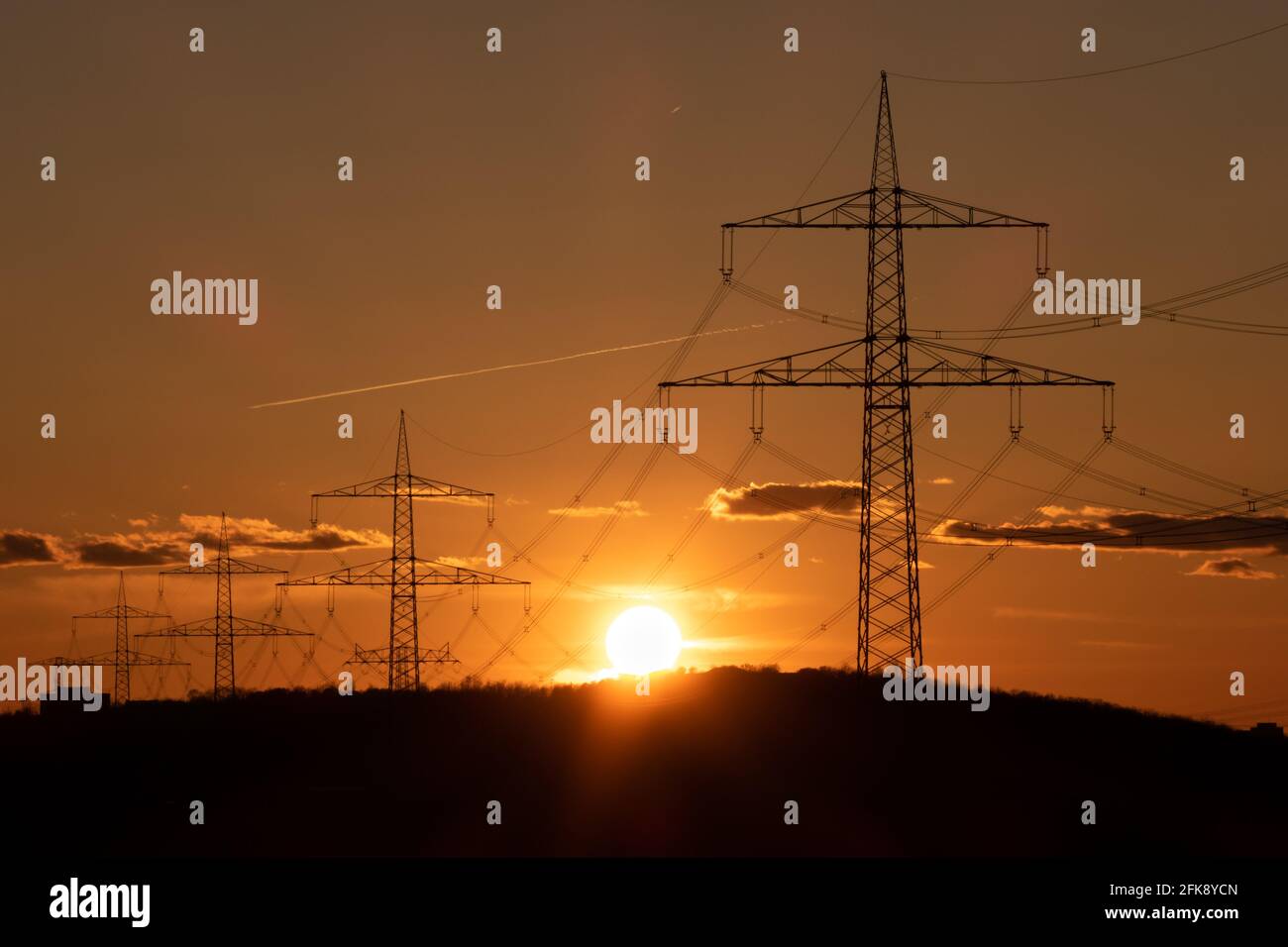 Electricity pylons with evening sun in the background. Stock Photo