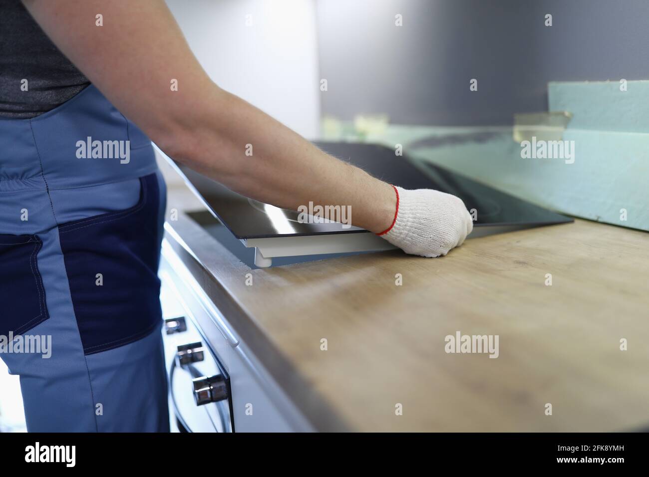 Master installs electric hob on kitchen cabinet Stock Photo
