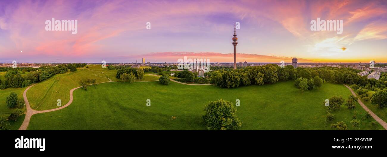 Dreamy sunrise over Munichs popular Olympic Park from a high and panoramic view with a violet morning sky over the sightseeing idyllic hotspot in the Stock Photo