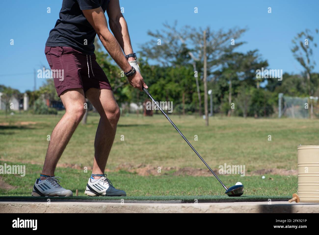 A young man about to strike a golf ball at a driving range Stock Photo