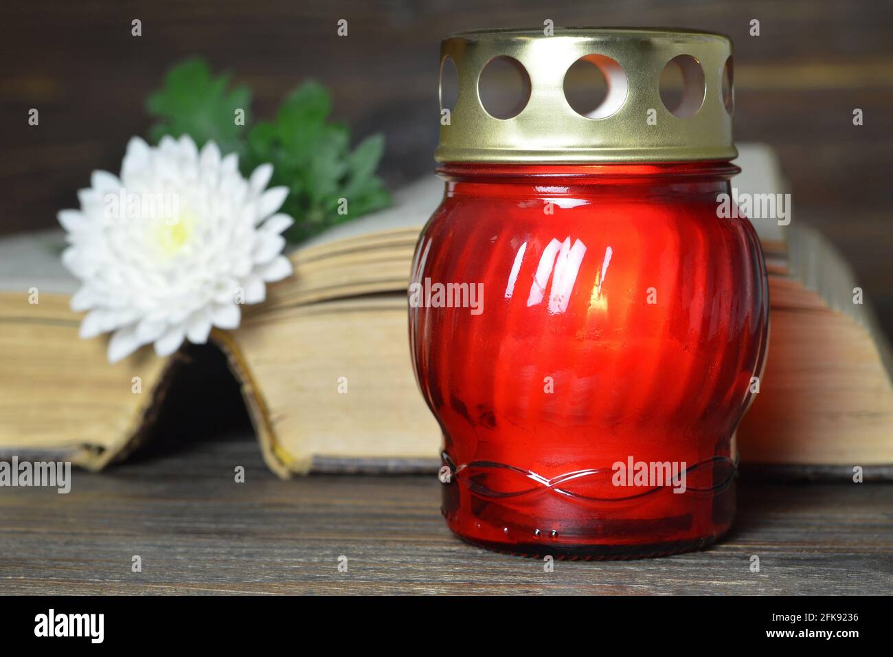 Red grave candle and white chrysanthemum flower on open book Stock Photo