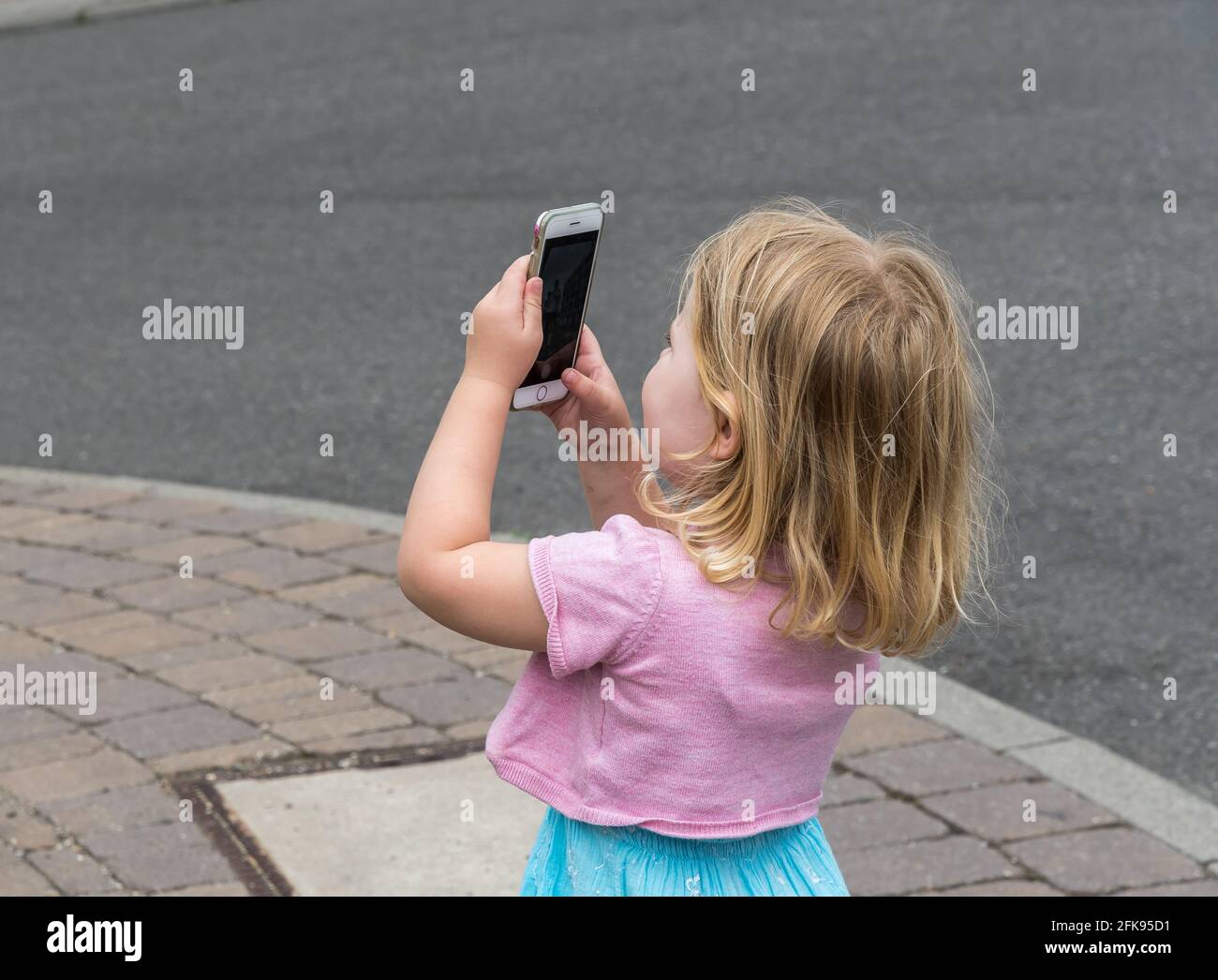 Little girl takes a photo with a smartphone Stock Photo