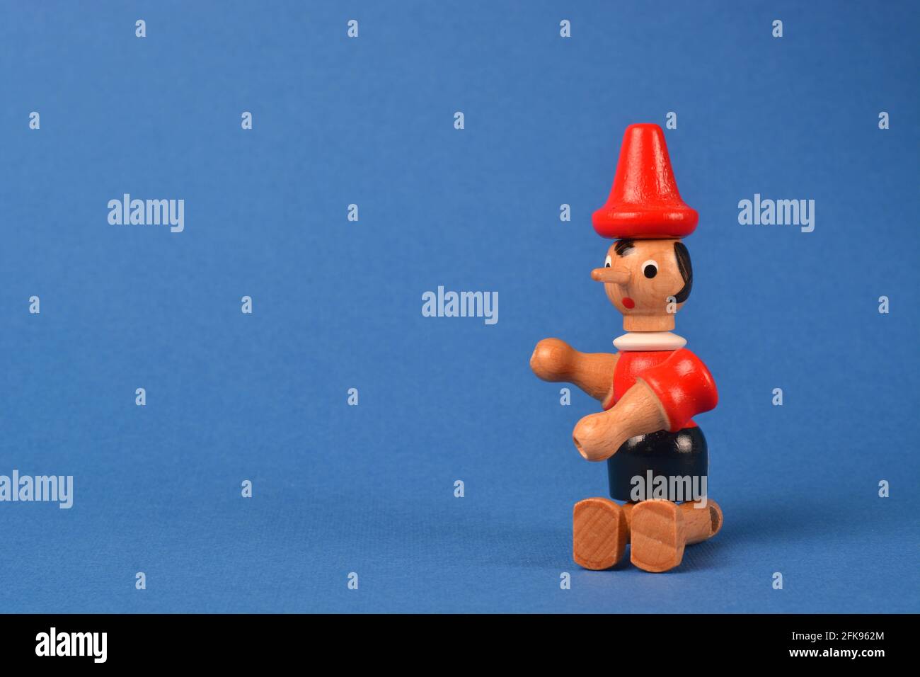 Wooden puppet depicting Pinocchio sitting on a blue background Stock