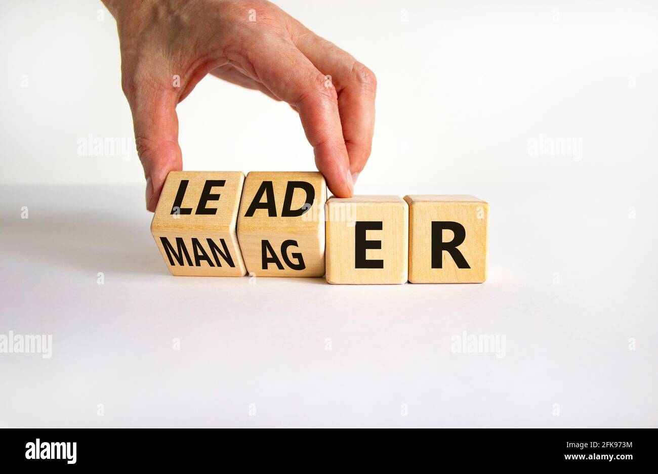 Manager versus leader symbol. Businessman turns wooden cubes and ...