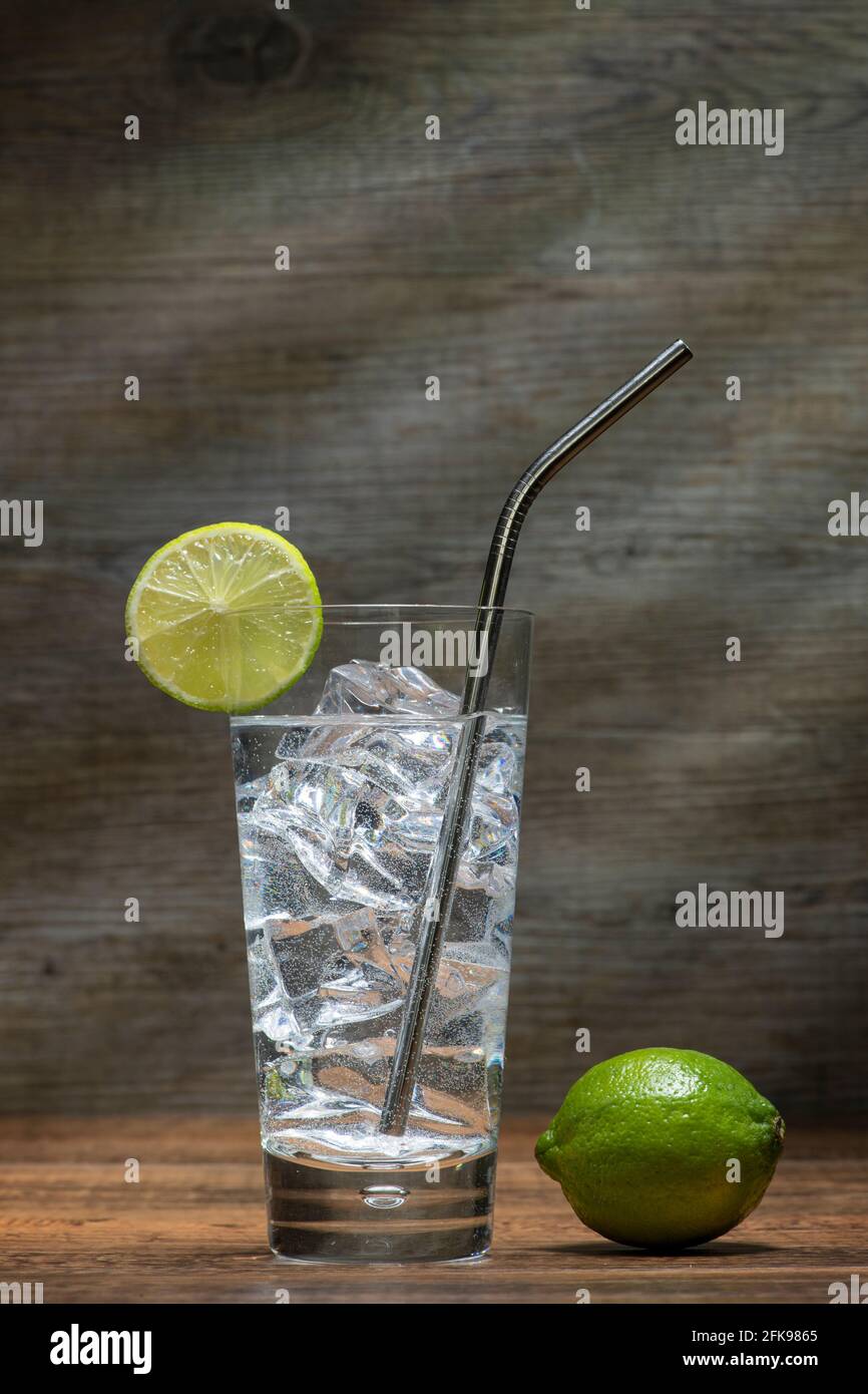Glass of water with ice and lime and a stainless steel straw in a highball glass. Stock Photo