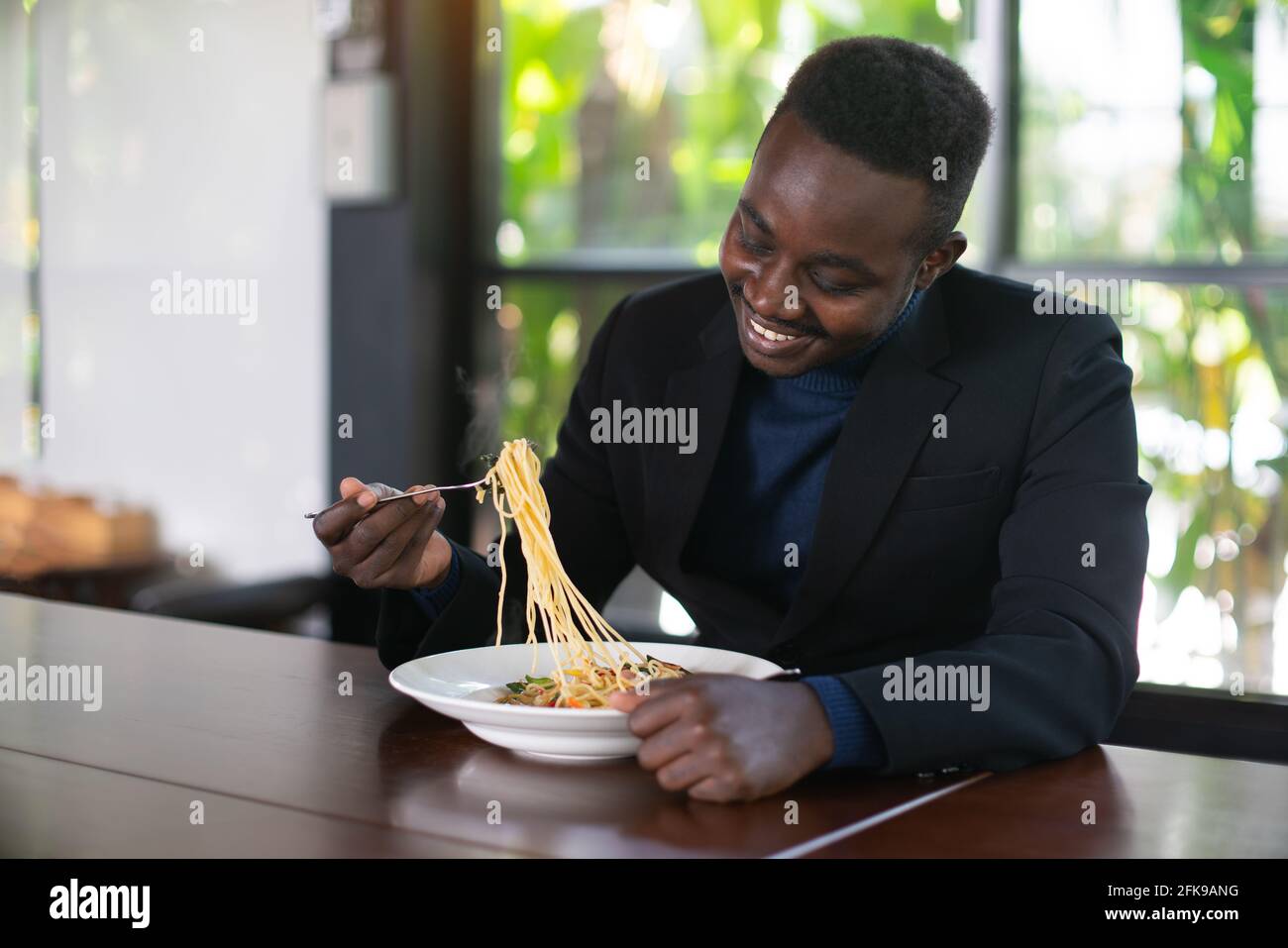 African businessman having a happy lunch with eating Spaghetti in restaurant Stock Photo