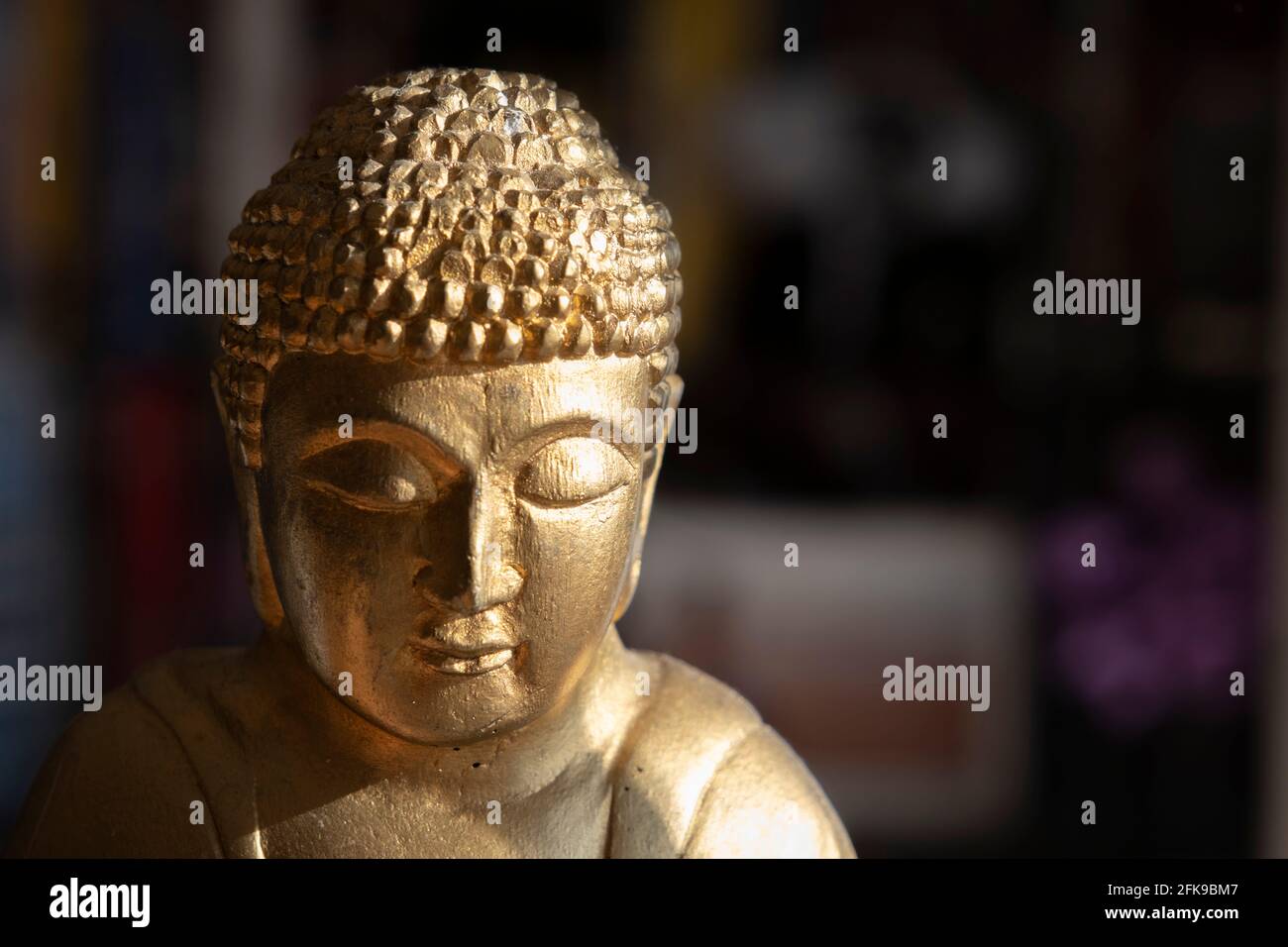 Buddhism and meditation concept: Close up on the head of a golden Buddha statue with copy space. Zen-like spirituality. Religious sculpture. Stock Photo