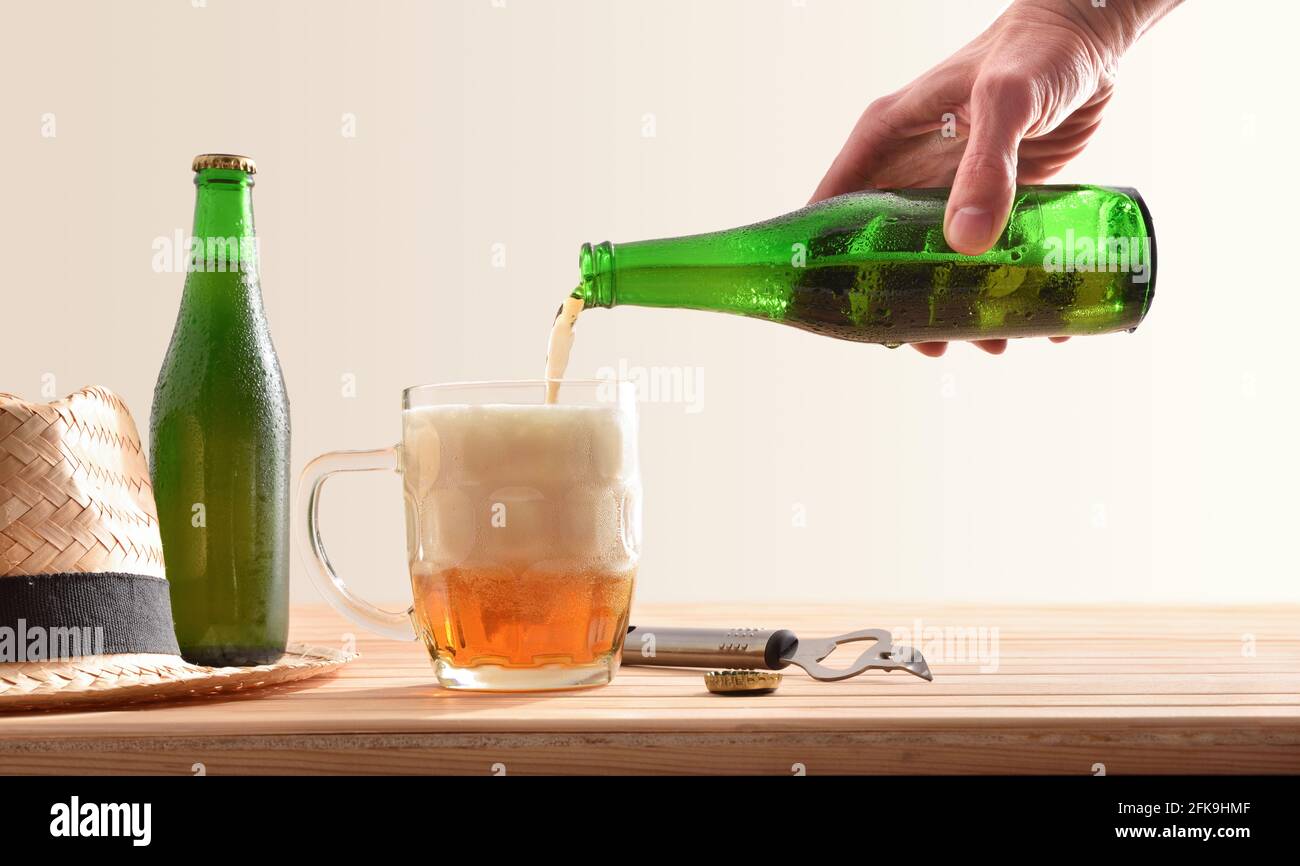 Serving in a beer mug with bottle and hat on wooden table isolated background Stock Photo