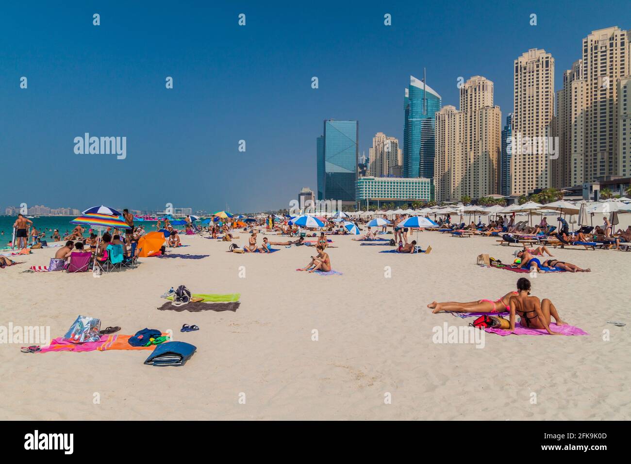 DUBAI, UAE - OCTOBER 21, 2016: People at Marina Beach in Dubai, United Arab Emirates. Jumeirah Beach Residence complex in the background. Stock Photo