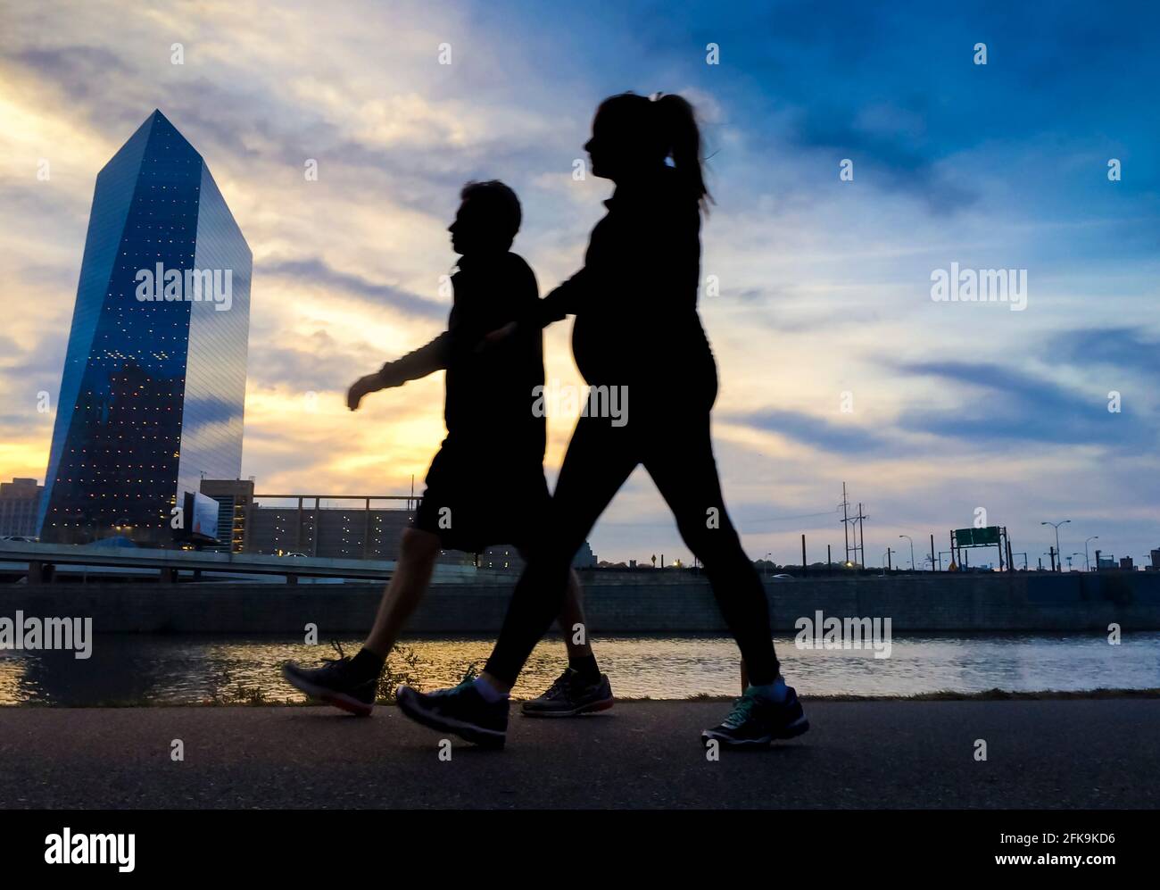 Jogger on Schuylkill River pathway at sunset with west Philadelphia skyline and Cira Center (designed by César Pelli) connected to Amtrak Stock Photo