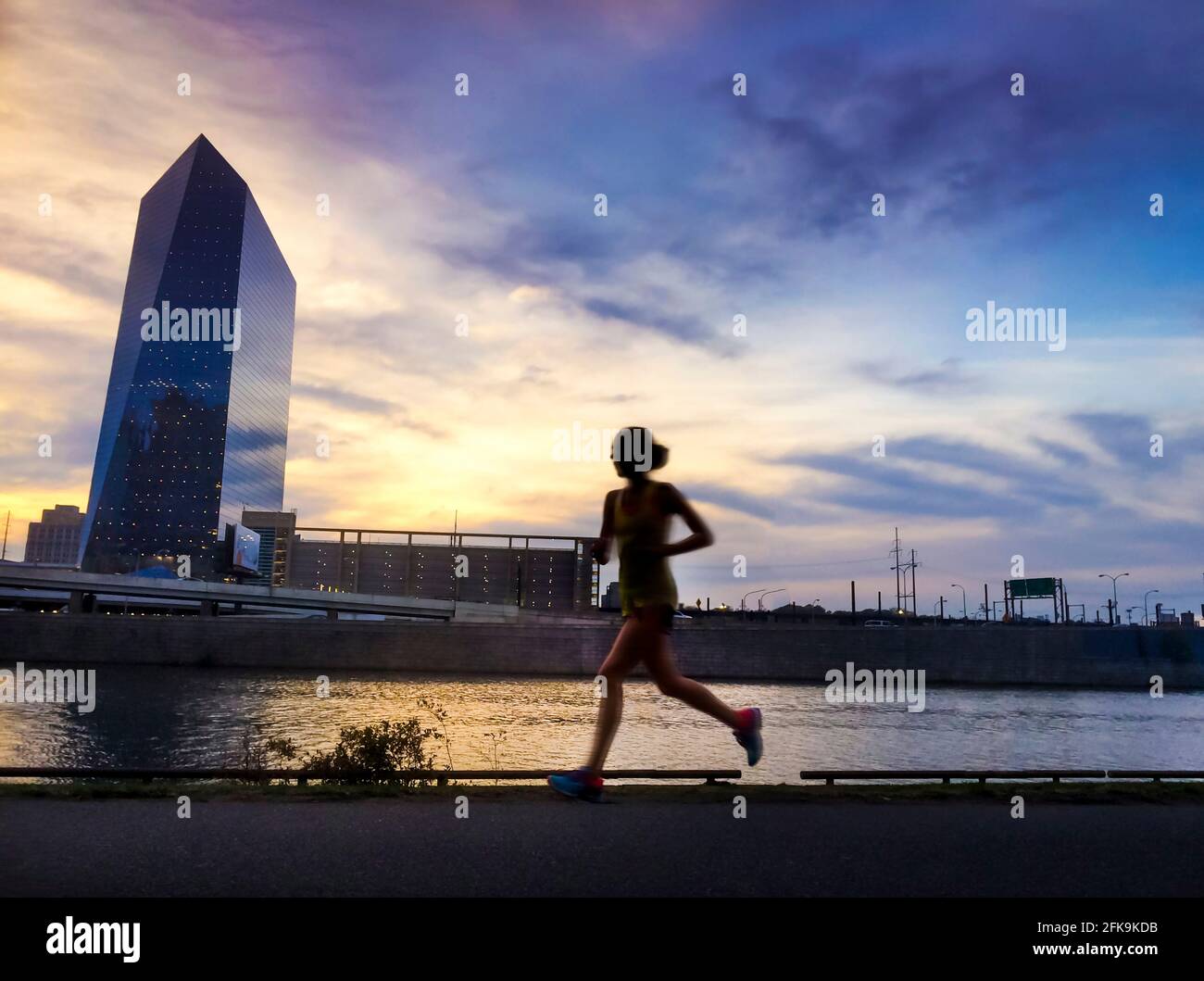 Jogger on Schuylkill River pathway at sunset with west Philadelphia skyline and Cira Center (designed by César Pelli) connected to Amtrak Stock Photo